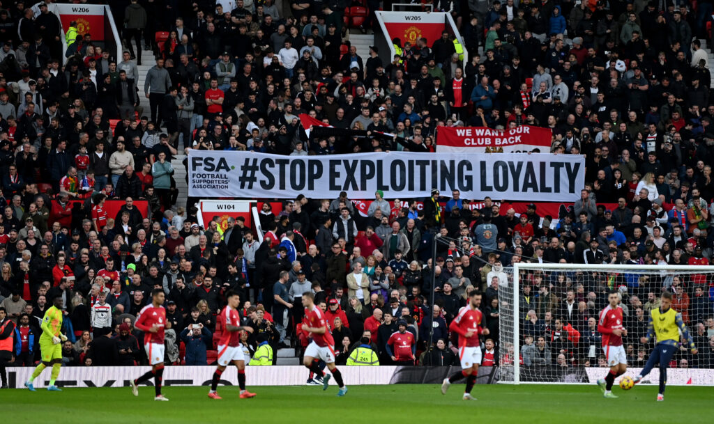Fans von Manchester United halten ein Banner mit der Aufschrift "Stop exploiting loyalty" hoch