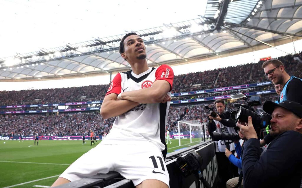 Hugo Ekitike sitzt im Fokus vieler Fotografen mit verschränkten Armen auf der Bande