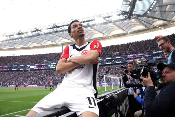 Hugo Ekitike sitzt im Fokus vieler Fotografen mit verschränkten Armen auf der Bande