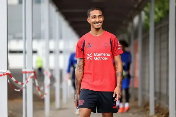 Arthur Bayer wearing a red Bayer 04 Leverkusen training shirt and black shorts, smiling outdoors.