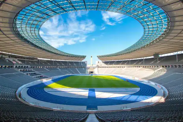 Wide interior view of the Olympiastadion Berlin with blue running tracks and a green grass pitch
